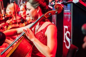 Susanne Röll im roten Kleid spielt Cello